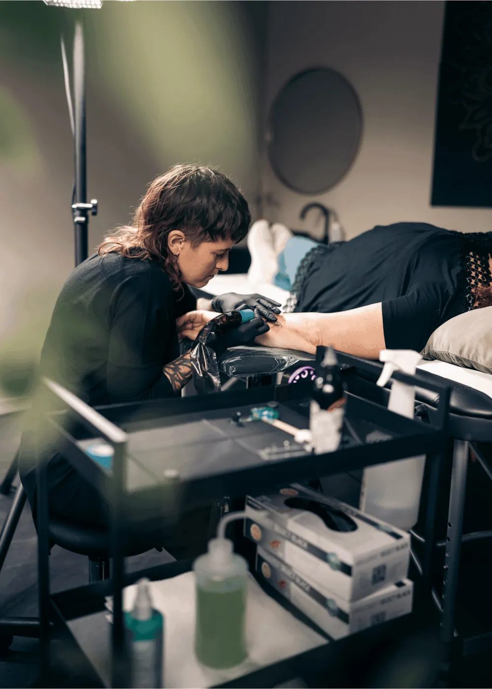 Tätowiererin bei der Arbeit an einem Bein im Studio