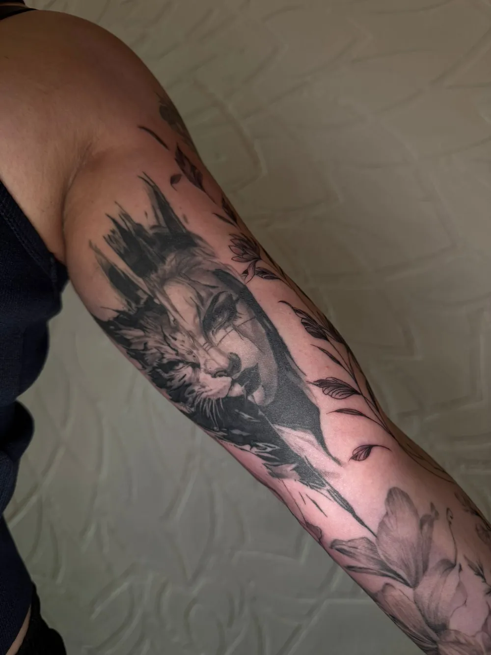 Oberarm-Tattoo mit Frauengesicht und Tiermotiv in Schwarz-Grau